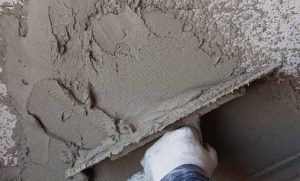 Applying traditional sand-and-cement render on training wall during our external rendering course